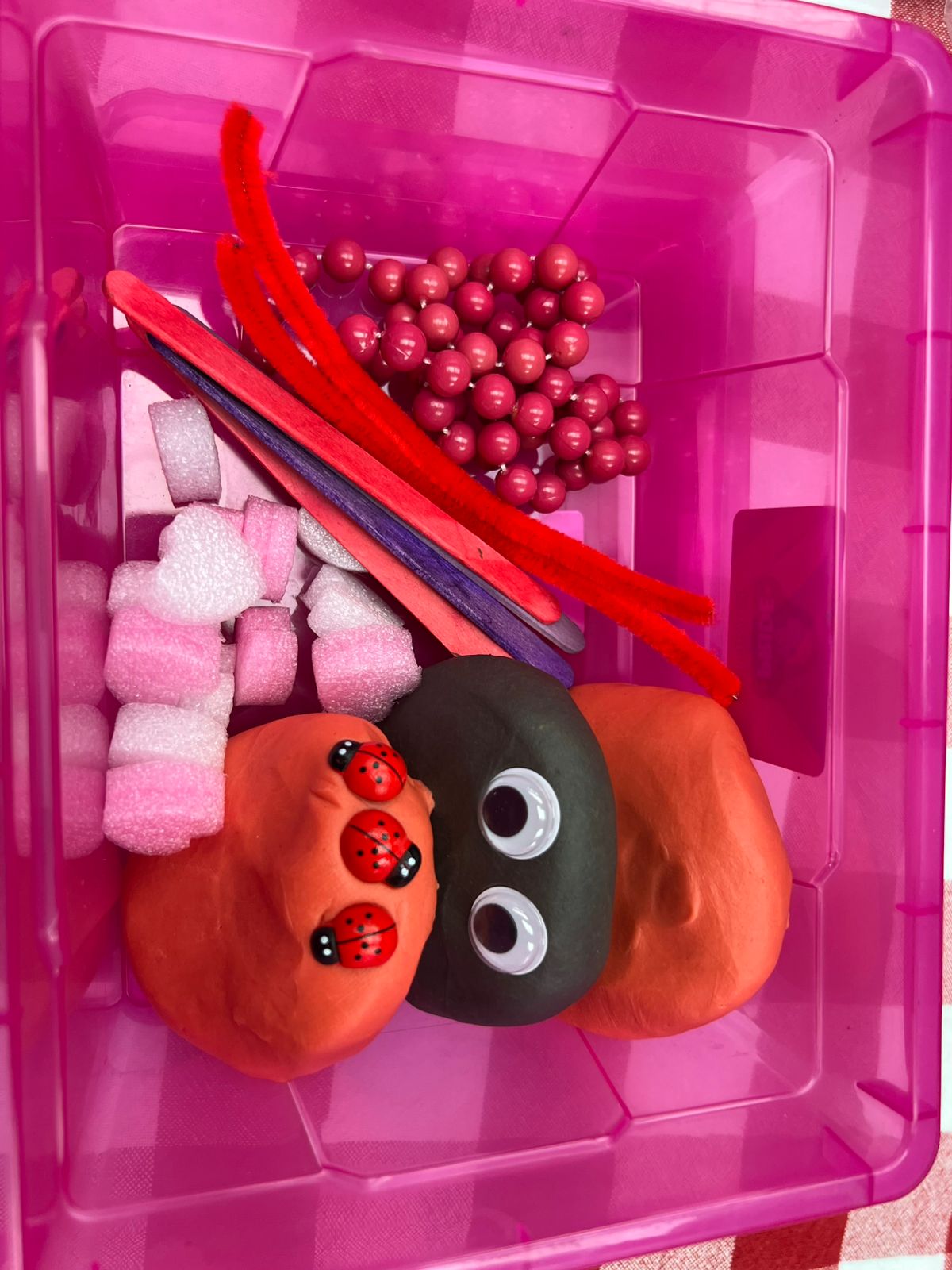 Pink container with play dough spider, beads, and straws